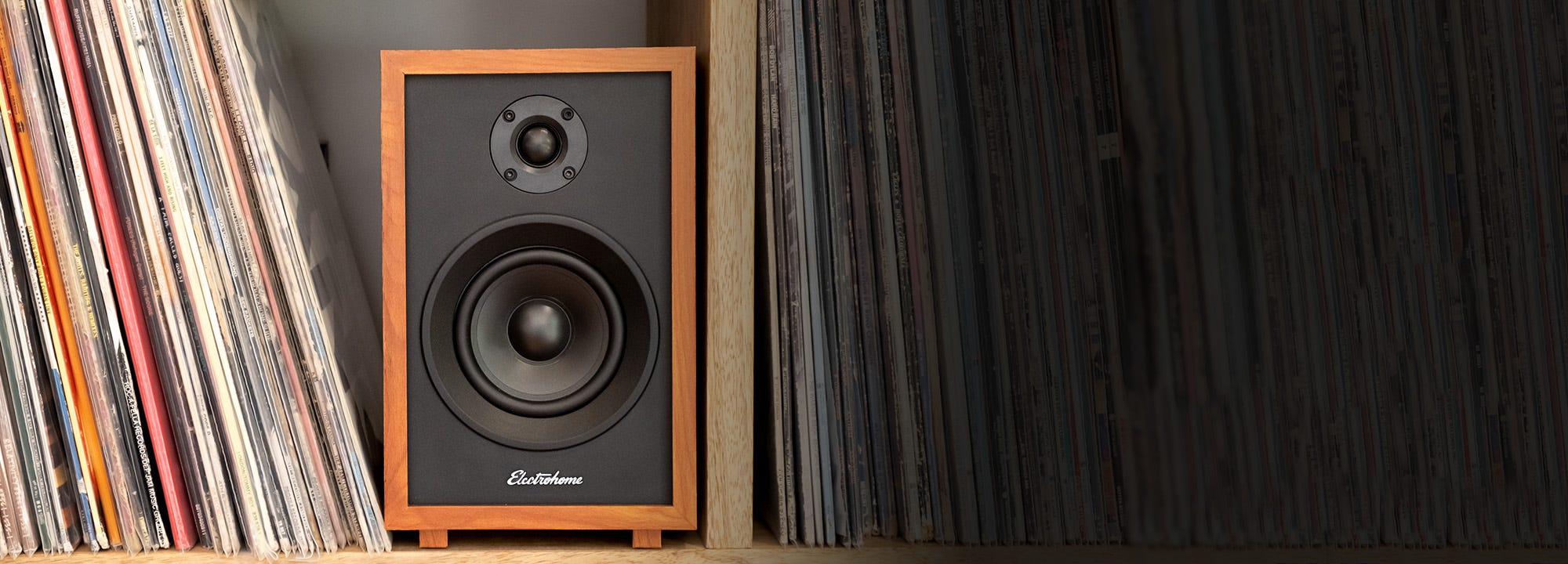 McKinkley Powered Bookshelf Speakers next to vinyl records